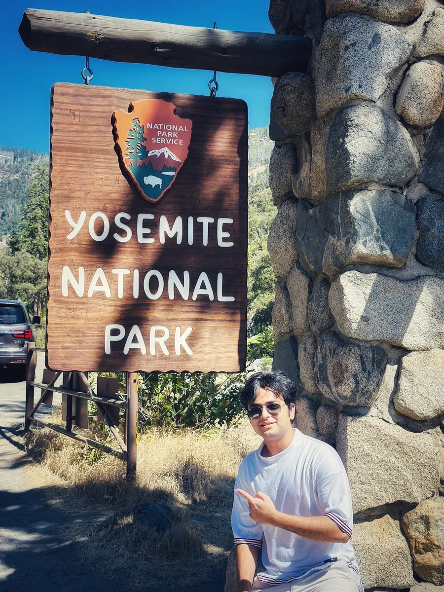 Akshay beside the Yosemite National Park entrance sign